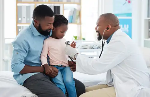 Father holding child while the doctor checks the childs heart with a stethoscope.