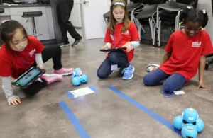 Kids learning about and programming small robotics in challenging games at Space Center Houston