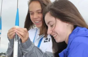 Teenage girls constructing small rocket on launchpad outside at Space Center Houston