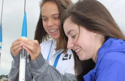 Teenage girls constructing small rocket on launchpad outside at Space Center Houston