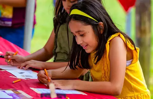 Bayou City Art Festival Memorial Park; two girls coloring and drawing at table during festival