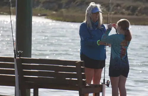 CCA-Texas-fishing-tournament-mother-showing-daughter-how-to-tie-fishing-lure-learning-to-fishjpg; Coastal Conservation Association Summer Fishing Tournament Adults Children Kids Texas College Scholarships Events Prizes