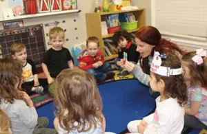 Faith West preschool students learning from teacher on rug in classroom