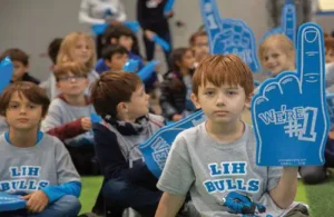 Group of kids cheering and wearing spirit wear for LIH; bilingual school