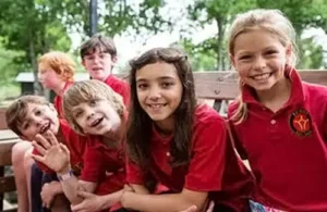 Gifted education; Group of smiling kids from Rainard School sitting on bench looking at camera; choice for gifted education