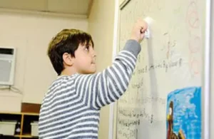 Student from Rainard School concentrating on solving problem at front of class