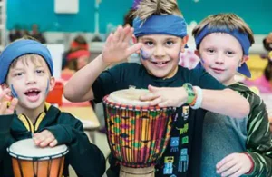 Boys banging on drums at Challenge Island Summer Camp