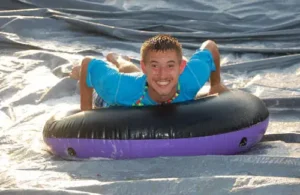 camper on slide with inner tube having fun; religious and special needs camps