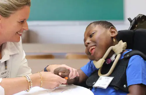 Child in wheelchair with disability working with teacher at The Caroline School