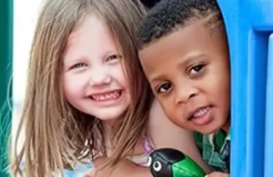 Two kids playing together on play equipment at The Children's Courtyard; daycare summer camps