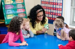 children sitting at table learning the alphabet from their teacher