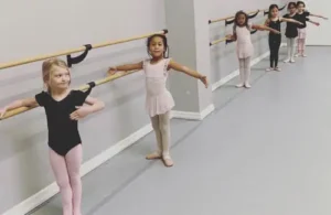 girls in ballet class holding railing at Iron Cross Gymnastics