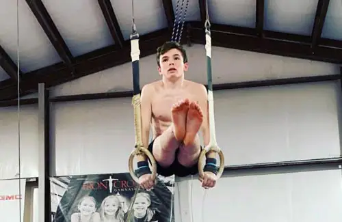 gymnast on rings holding self up with legs straight out