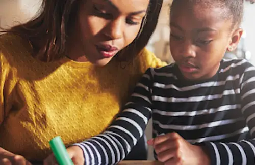 mother helping child with schoolwork at desk; academic testing