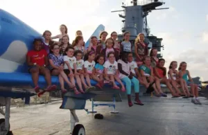 Group of kids sitting on a jet on the flight deck of the USS Lexington