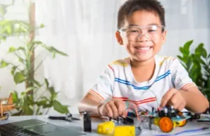 Kid sitting at table building his robotic car at Learn to Bot; coding robotics summer camp.