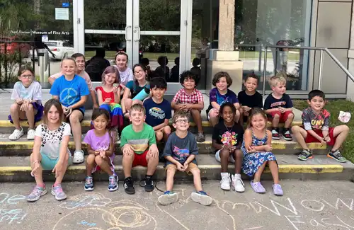 Summer art camp kids sitting on the front steps of the Pearl Fincher Museum of Fine Arts.