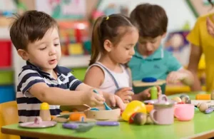 Young kids at table pretending to prepare and cook food