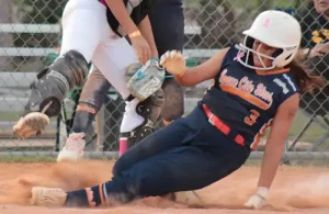 MAGSA softball player sliding in to base with catcher jumping in air