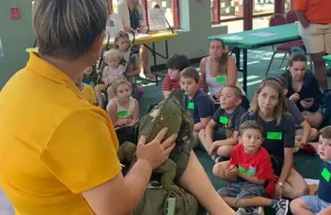 Instructor showing large reptile to kids at Moody Gardens summer camp.