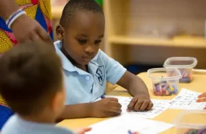 Silverline Montessori students sitting at a table completing schoolwork with teacher assistance
