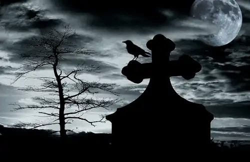 Creepy setting in cemetery with crow standing on headstone.