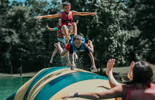 Camp Huawni Overnight Summer Camp -Campers at Camp Huawni jumping on water critter bounce blob.