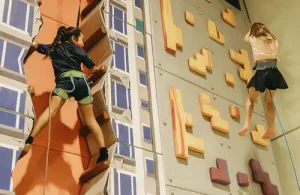 Kanga's Indoor Playcenter In Cypress climbing an indoor rock wall with support line.