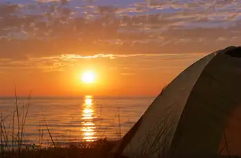 Discover the Best Coastal Campgrounds in Texas for Families blog article main image; camping tent at the beach at sunset; nature - wildlife - outdoor adventures.