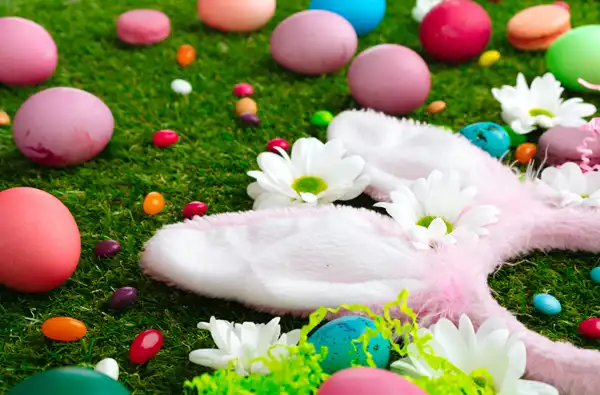 The Ultimate Easter Survival Guide for parents main image showing bunny ears headband, easter eggs, and jelly beans laying on fake grass.