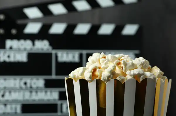 Main image for Free Family-Friendly Outdoor Movies 2026 blog article; clap board in back of a bucket of popcorn.