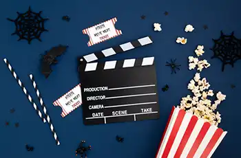Halloween Movie Night Ideas for Families With Kids main image showing movie props, popcorn, movie clapper, and halloween accessories.