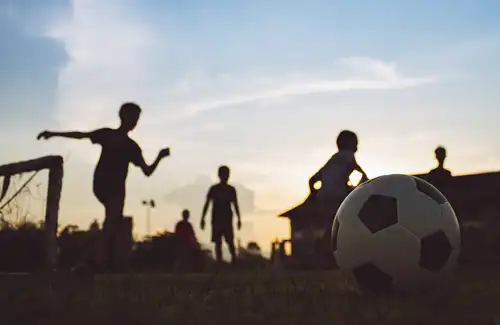 Texas A&M Aggie Soccer Camp kids playing soccer on the field at dusk.